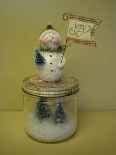 a snowman sitting on top of a glass jar