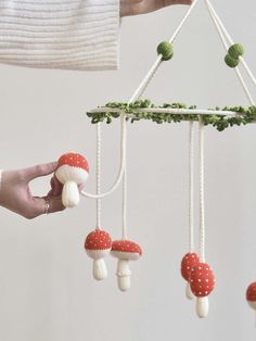 a person is holding a mobile with mushrooms hanging from it's sides and string attached to the strings