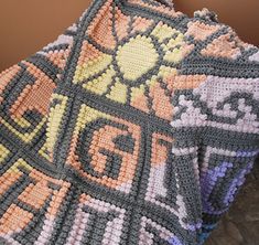 a crocheted blanket sitting on top of a wooden floor next to a wall