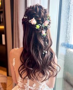 the back of a woman's head with flowers in her hair, looking out a window