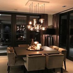 a dining room table and chairs with candles on it in front of large glass doors