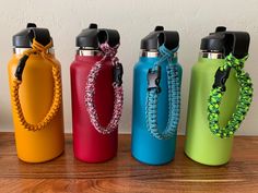 four different colored water bottles on a wooden table