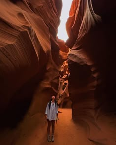 a woman standing in the middle of a narrow canyon