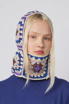 a woman with blonde hair wearing a crochet head scarf and blue sweater over her face