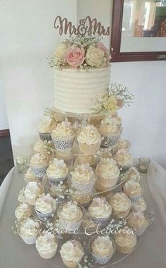 a wedding cake and cupcakes on a table