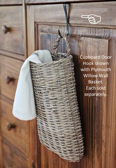 a basket hanging on the side of a wooden cabinet with a white towel tied to it