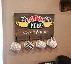 coffee cups are hanging on the wall above a sign that says central perk coffee