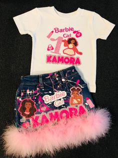 a t - shirt and denim skirt with pink feathers on the bottom are sitting next to each other