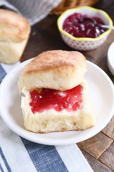 a biscuit with jam on it sitting on a plate next to a bowl of jelly