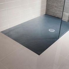 a bathroom with a glass shower door on the floor and tile wall behind it,