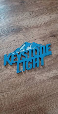 a metal sign that says keystone tight on top of a wooden floor with a mountain in the background