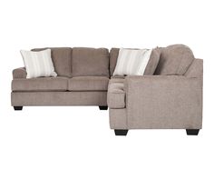 a sectional couch with pillows on it and a white pillow in the back ground next to it