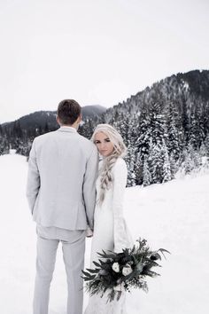 a bride and groom standing in the snow