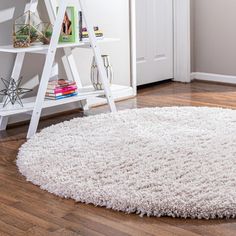 a white rug on the floor in front of a book shelf with books and magazines