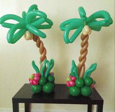 two palm trees made out of balloons sitting on top of a wooden table next to a wall