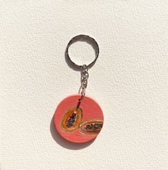 a keychain with a piece of fruit hanging from it's side on a white surface