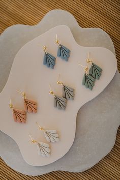 six pairs of earrings on a white plate