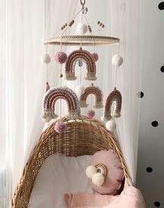 a baby crib with a rainbow mobile hanging from it's side, next to a teddy bear