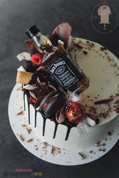 a white cake topped with lots of different types of candies and liquor bottles on top of it