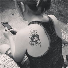 a woman with a tattoo on her back holding a cell phone and looking at the screen