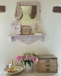 a vase with flowers and other items on a table in front of a wall mirror