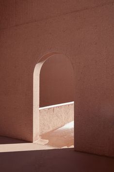 an arch in the side of a building with light coming through it and shadows on the ground