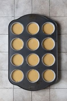 cupcakes are lined up in a muffin tin on the floor, ready to go into the oven