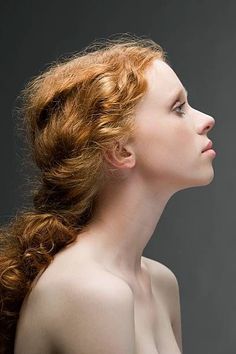 a woman with red hair is posing for the camera and has her head turned to the side