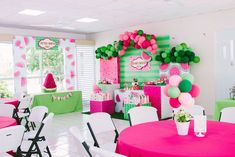 a room filled with tables covered in pink, green and white balloons