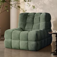 a green reclining chair sitting on top of a table next to a potted plant