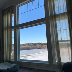 there is a dog bed in front of the large window that looks out onto the snow covered field