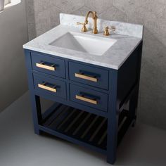 a white sink sitting under a mirror next to a blue cabinet with gold pulls on it