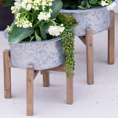 two metal planters with white flowers in them