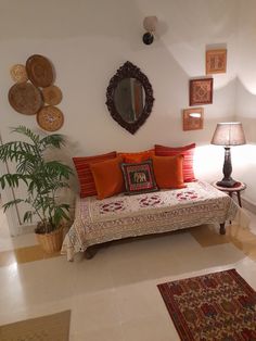 a living room filled with lots of furniture next to a wall mounted mirror and potted plant