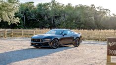 a black car parked in front of a wooden fence