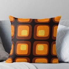 an orange and brown throw pillow sitting on top of a couch