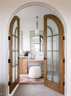 an arched doorway leading to a bathroom with a white stool and mirror on the wall