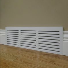 a white radiator cover sitting on top of a hard wood floor next to a wall