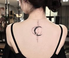 the back of a woman's neck with a crescent tattoo on her left shoulder