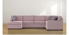 a pink sectional couch with pillows on it