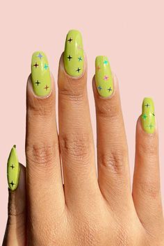 a woman's hand with green nail polish and stars on the tip of her nails