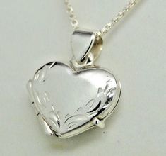 "Photos are precious and here's a lovely way to keep those memories close. Our beautifully worked genuine 925 sterling silver heart picture locket has a hand engraved leaf border along the heart shape itself - so each is a unique work of art. There's also a secure compartment inside to hold two special photos. Our picture locket in genuine sterling silver is small, measuring approx. 5/8\" wide by 3/4\" long - it works as a pendant or as a charm on a bracelet. A lovely piece of jewelry for a youn Luxury Sterling Silver Locket Necklace, Classic Heart-shaped Sterling Silver Locket Necklace, Classic Heart Shaped Sterling Silver Locket Necklace, Classic Sterling Silver Heart Locket Necklace, Engraved Sterling Silver Heart Necklace For Memorials, Sterling Silver Heart Locket Necklace For Memorial, Silver Double Heart Locket Necklace, Sterling Silver Locket Necklace For Mother's Day Anniversary, Sterling Silver Locket Necklace For Anniversary On Mother's Day