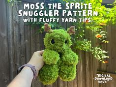 a hand holding a green stuffed animal with the words moss the sprite snuggler pattern