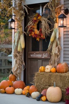 pumpkins and gourds are arranged on the front porch for fall decorating