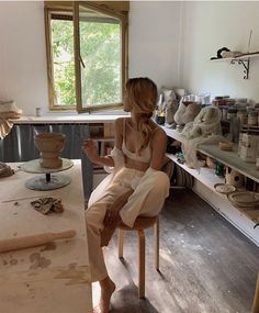 a woman sitting on a chair in a room filled with pottery and knick knacks