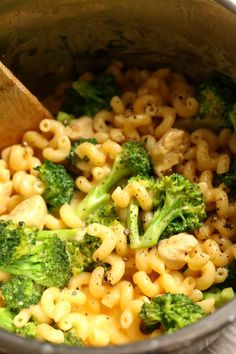 a pot filled with macaroni and broccoli on top of a wooden spoon