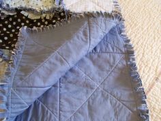 a blue quilted blanket laying on top of a bed next to a polka dot pillow