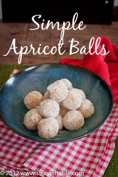 a bowl filled with powdered sugar balls on top of a red and white checkered cloth