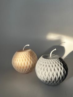 two white and black vases sitting next to each other on a gray table top