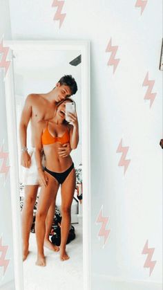 a man and woman standing in front of a mirror